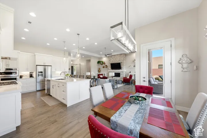 Open-concept living space with wood-finish flooring, a kitchen island with seating, white cabinetry, and stainless steel appliances