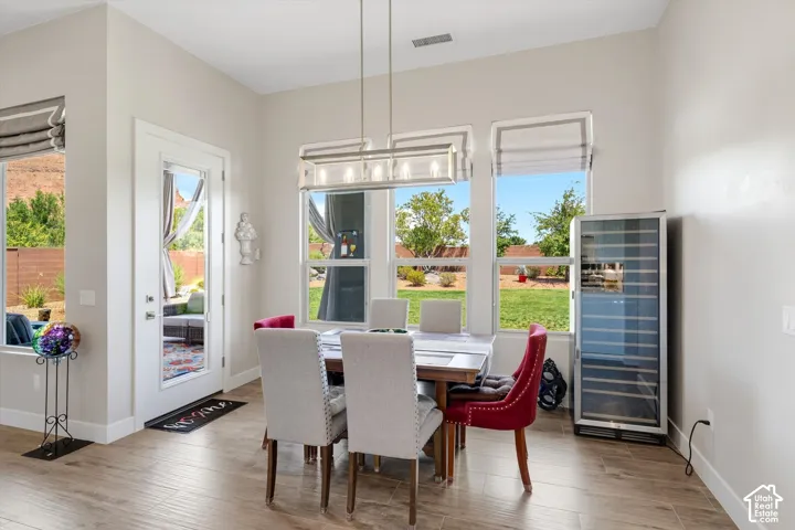 Dining area with wood-finish flooring, multiple windows, a glass-paneled exterior door, and a built-in beverage cooler