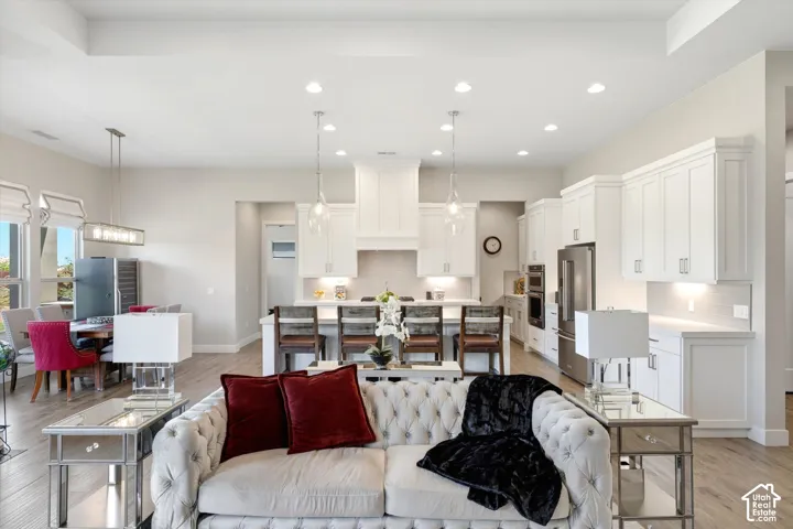 White shaker cabinetry, stainless steel appliances, recessed ceiling lights, wood-finish flooring, and an open-concept layout