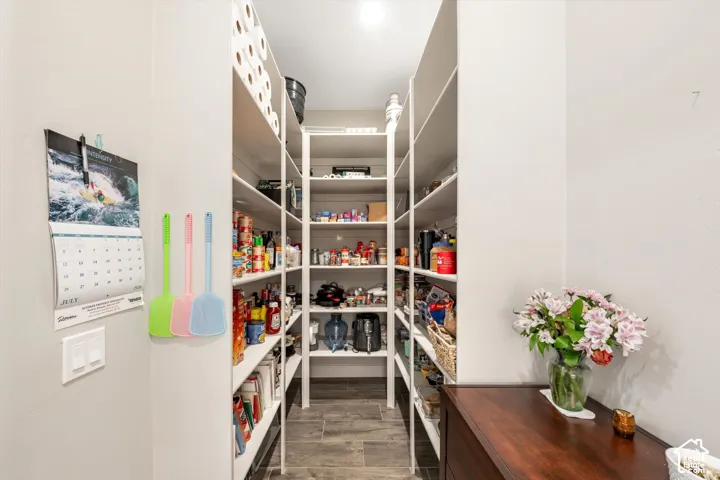 Spacious pantry featuring extensive white shelving and wood-finish flooring