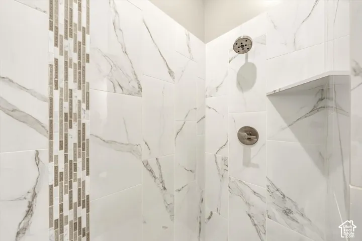 Tiled shower with a vertical mosaic accent, built-in shelving, and a brushed nickel showerhead and control