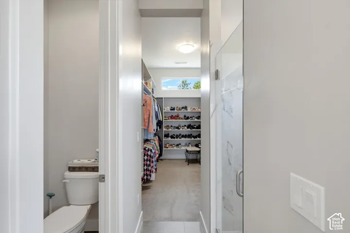 Recessed lighting, built-in shelving, glass shower enclosure, upper transom window, and neutral wall tones