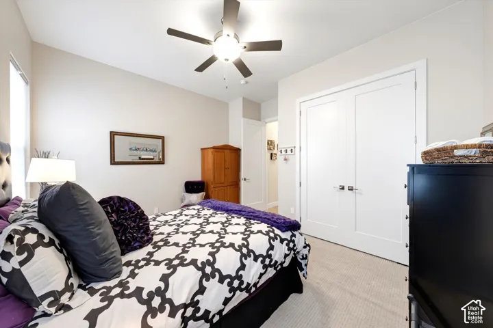 Carpeted flooring, vaulted ceiling, ceiling fan with integrated lighting, and white panel doors with contemporary hardware