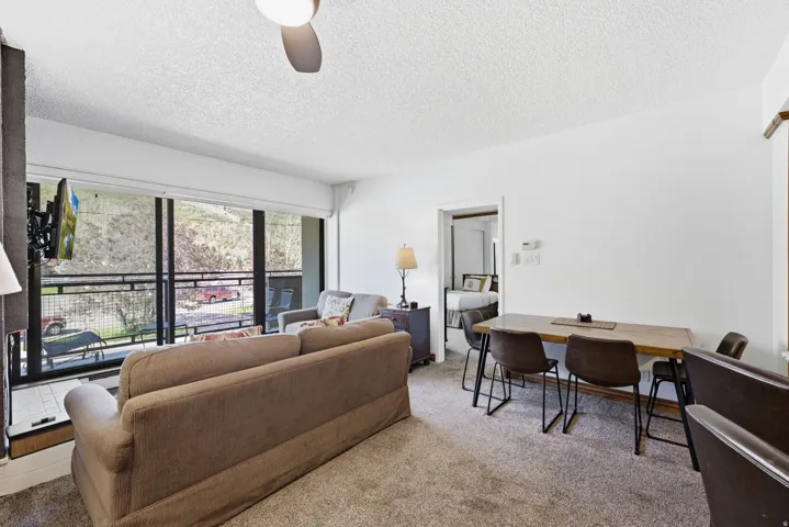 Living area with a ceiling fan, wall-mounted television, and floor-to-ceiling windows