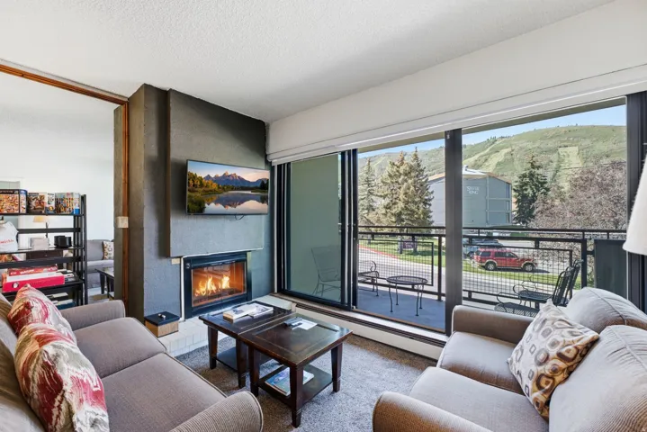 Built-in fireplace with hearth, television mounted above, and sliding glass doors opening to an exterior balcony