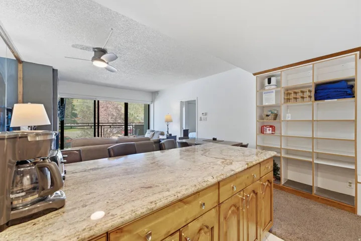 Kitchen island with a granite countertop, wood cabinetry, and built-in shelving