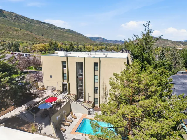Multi-story building with a stucco exterior, multiple balconies, and an outdoor swimming pool