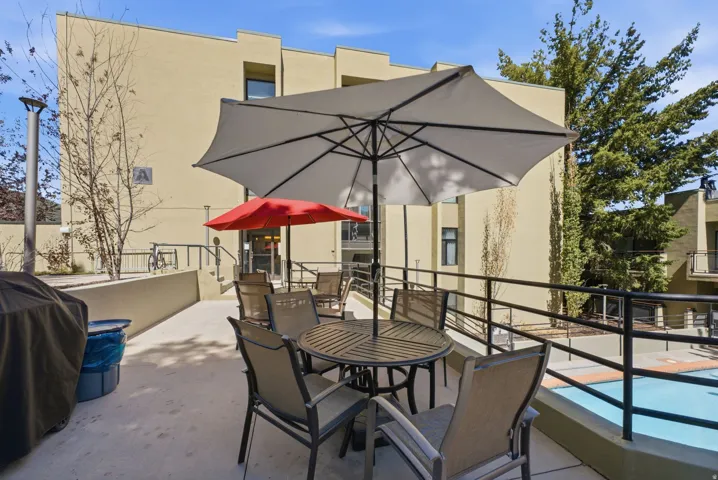 Outdoor patio area with a light-colored building facade and a pool