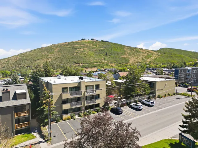 Multi-story building with balconies, surface parking, and mountainous topography in the background