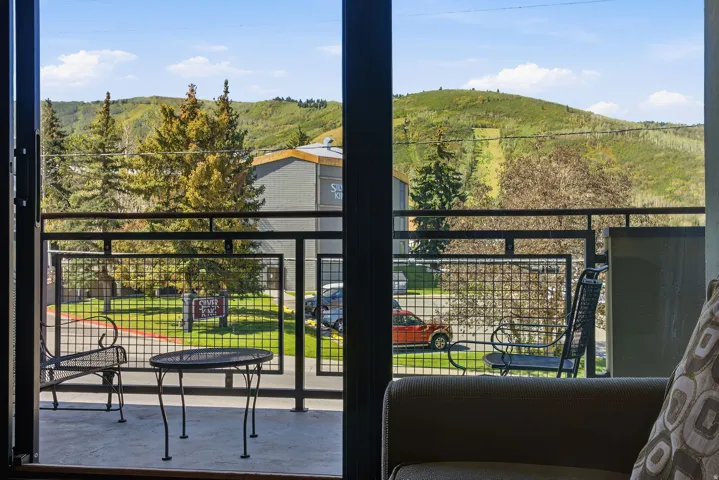 Balcony with black metal railing and concrete flooring overlooking a green landscape with distant hills