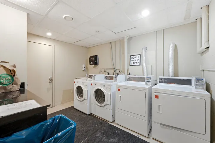 Dedicated laundry room featuring multiple front-loading washers and dryers, recessed lighting, and durable flooring