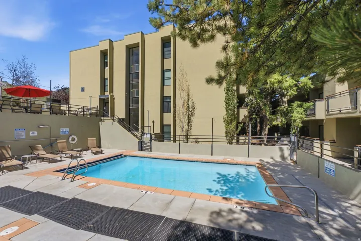 Outdoor swimming pool with a concrete pool deck, terracotta-colored coping, and metal railings