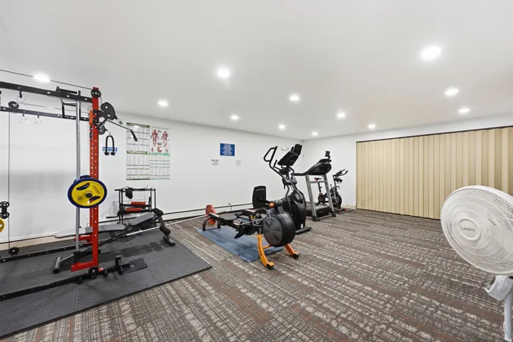 Dedicated fitness area featuring recessed lighting, carpet flooring, and accordion-style wall partitions