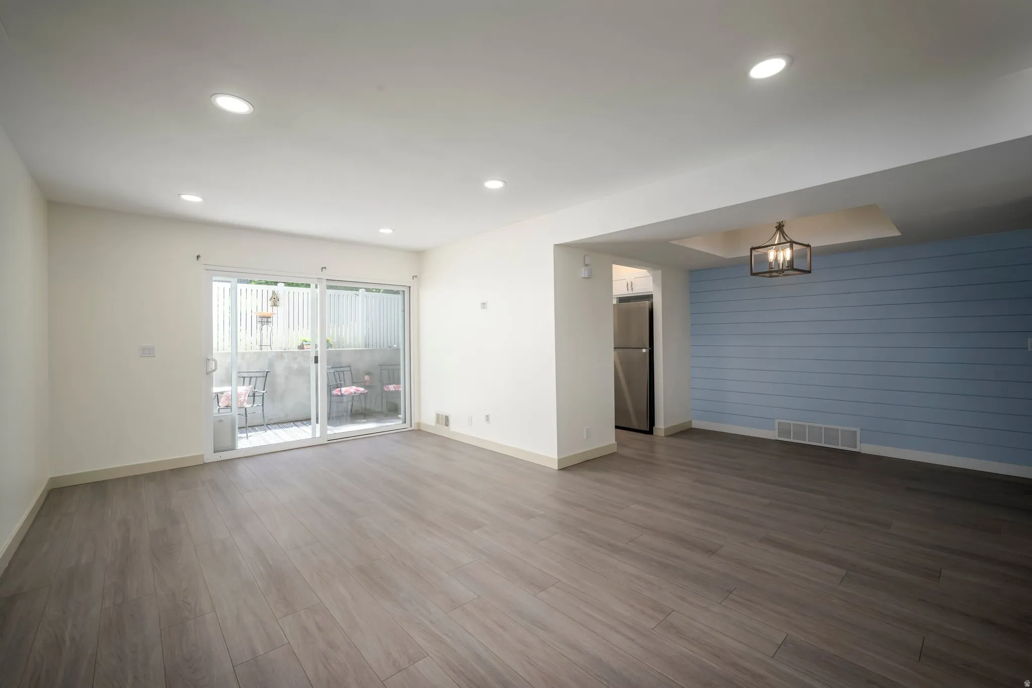 Wood-finish flooring throughout, recessed lighting, and a sliding glass door