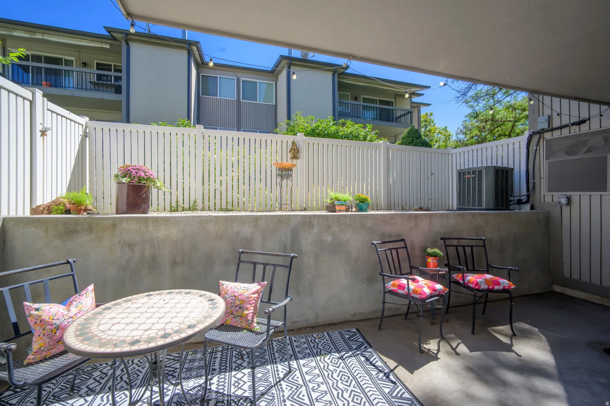 Private patio area featuring a concrete surface and a white privacy fence
