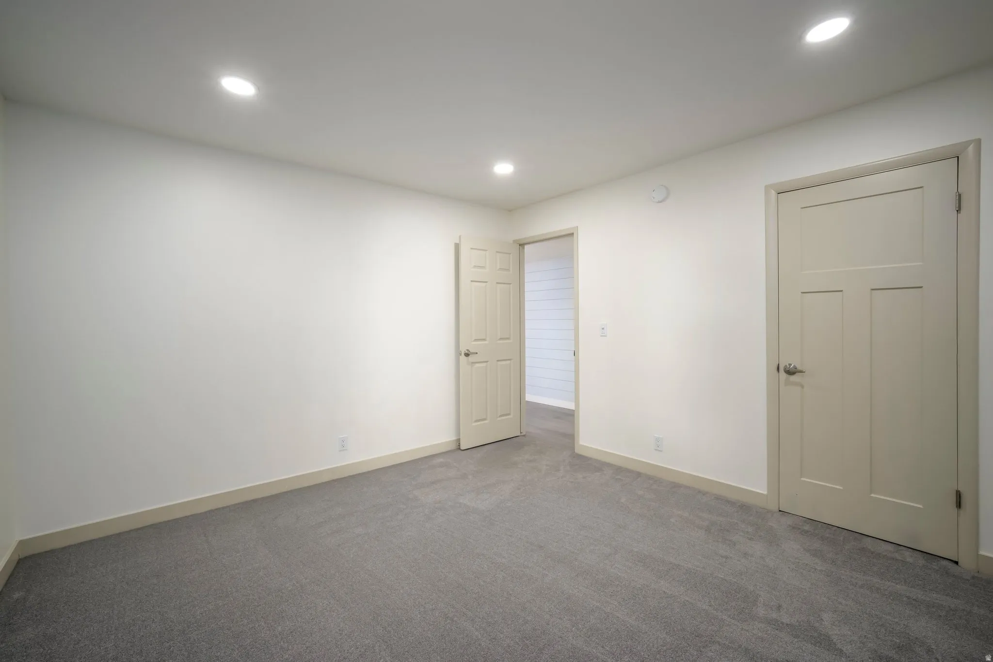 Recessed ceiling lighting, neutral carpeting, beige interior doors, and a neutral wall color