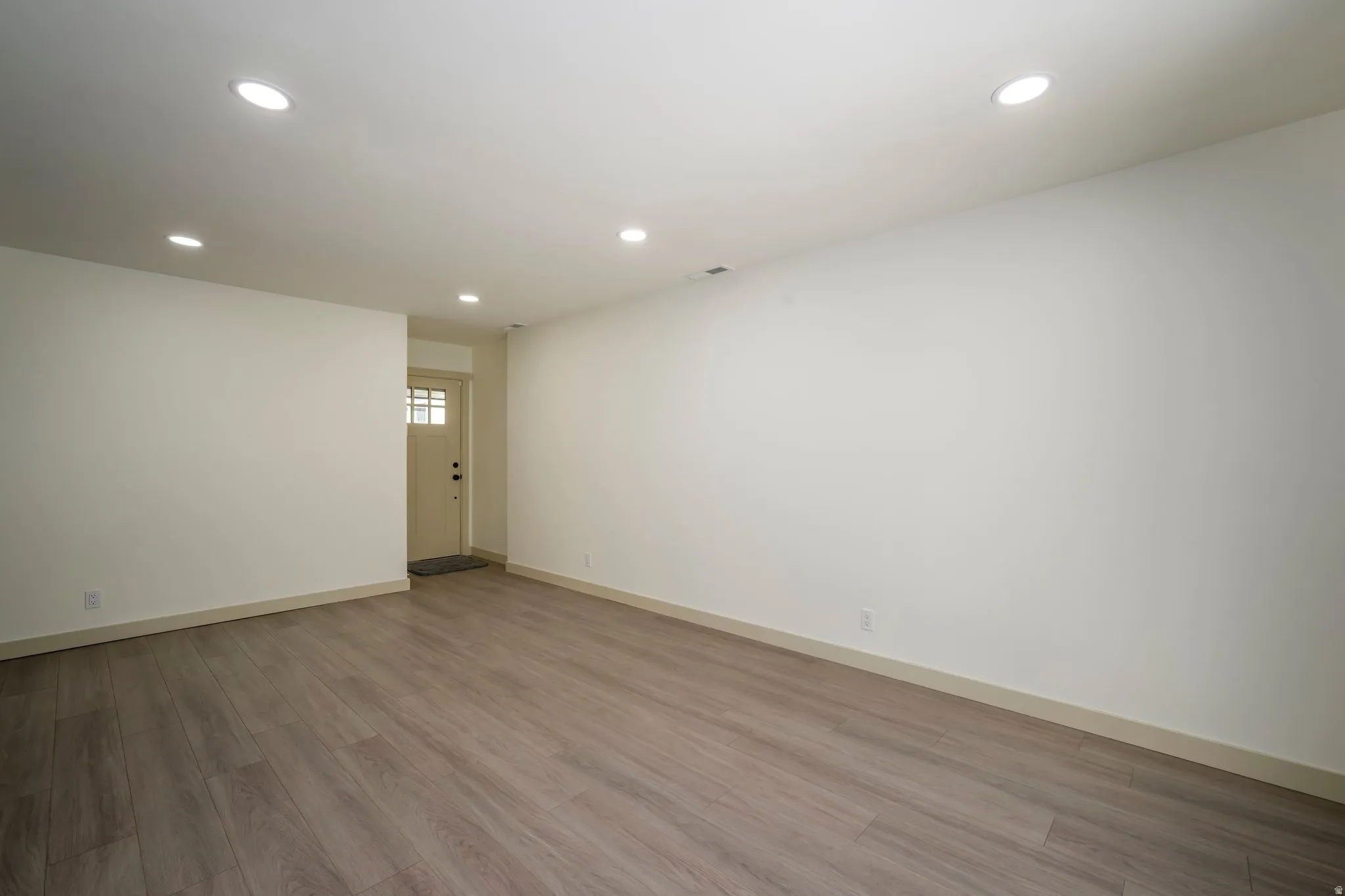 Recessed ceiling lighting, wood-finish flooring, and a paneled entry door with frosted glass inserts