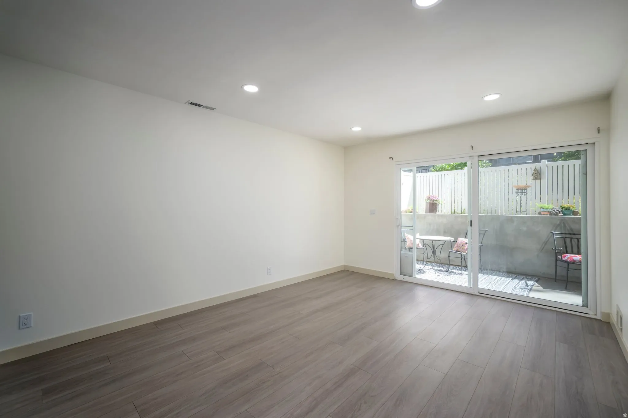 Recessed lighting, wood-finish flooring, sliding glass door, private patio, and privacy fencing
