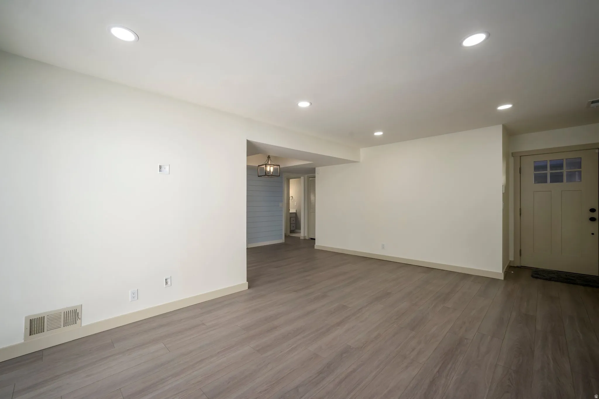 Recessed lighting, wood-finish flooring, white trim, and a panel door with window inserts