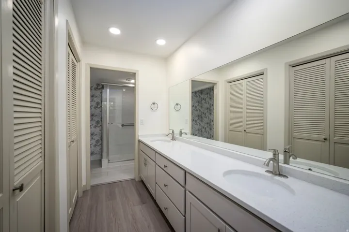 Double vanity with undermount sinks, stone-finish countertop, brushed nickel faucets, and wood-finish flooring