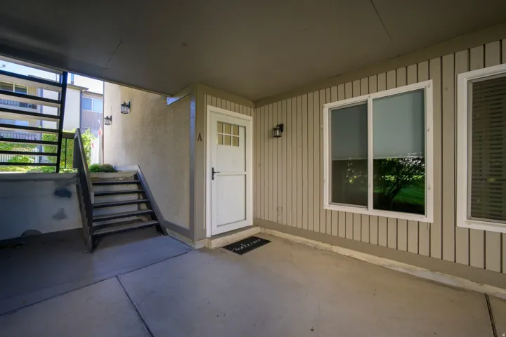 Entryway featuring a white paneled door with glass inserts, exterior wall sconces, and a concrete patio