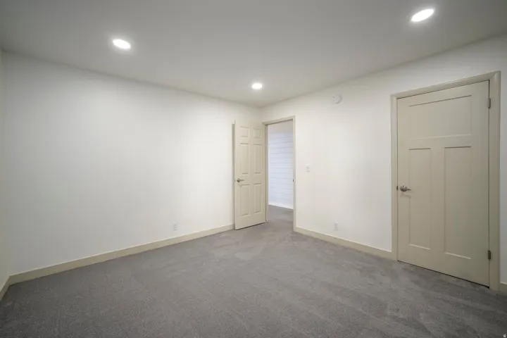 Recessed ceiling lighting, neutral carpeting, beige interior doors, and a neutral wall color