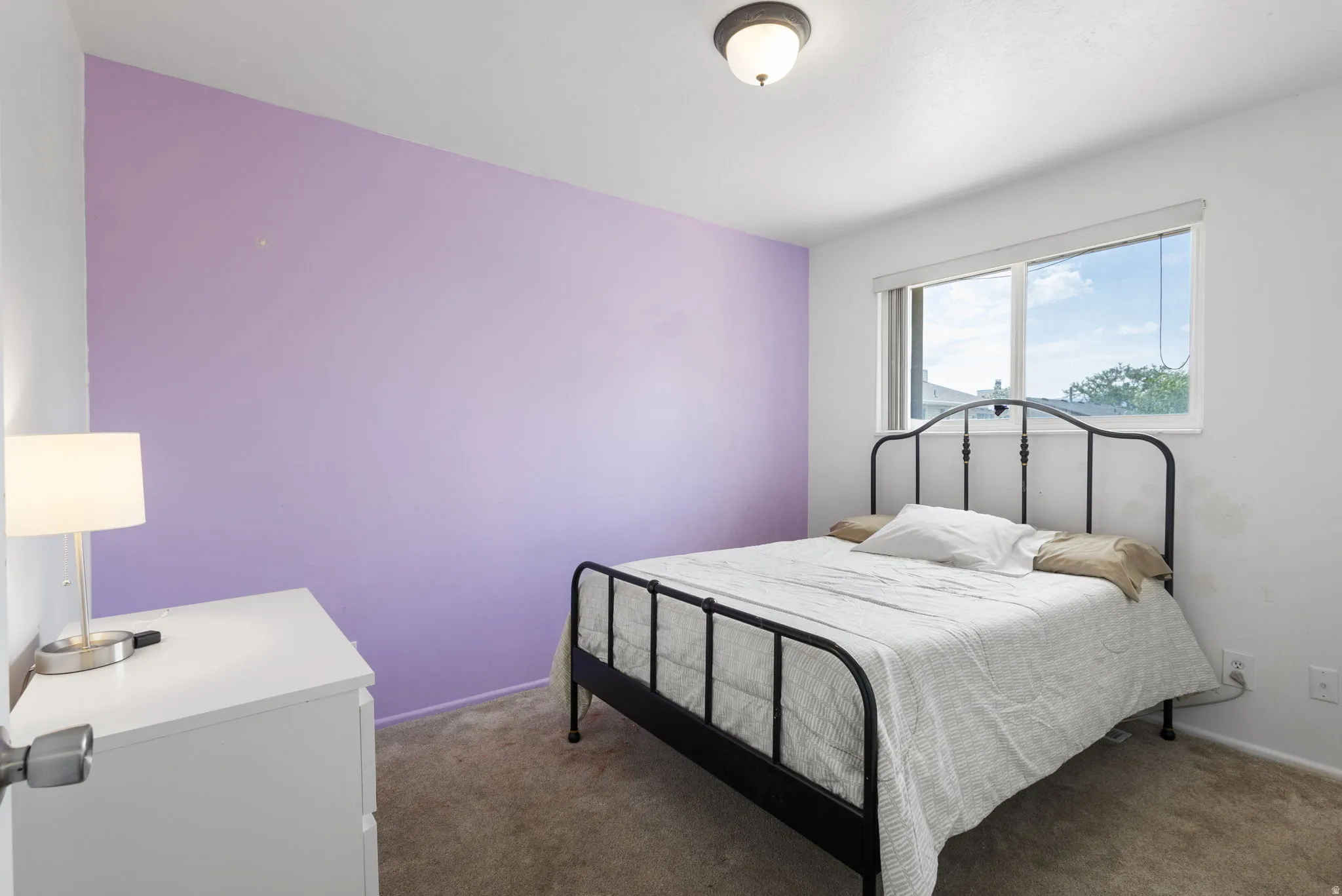 Carpeted room with a single window and ceiling-mounted light fixture