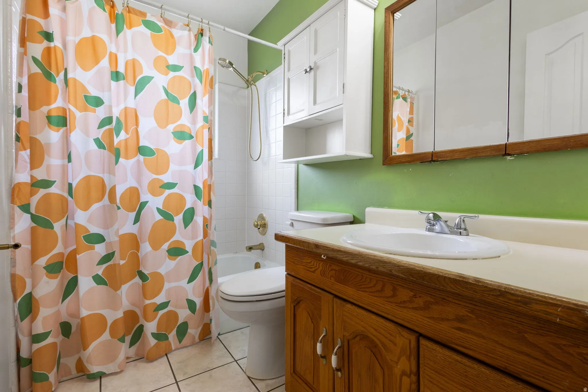 Bathroom featuring a wood-finish vanity with an integrated sink, a built-in medicine cabinet, a full-size bathtub with white tile surround, and an overhead storage cabinet