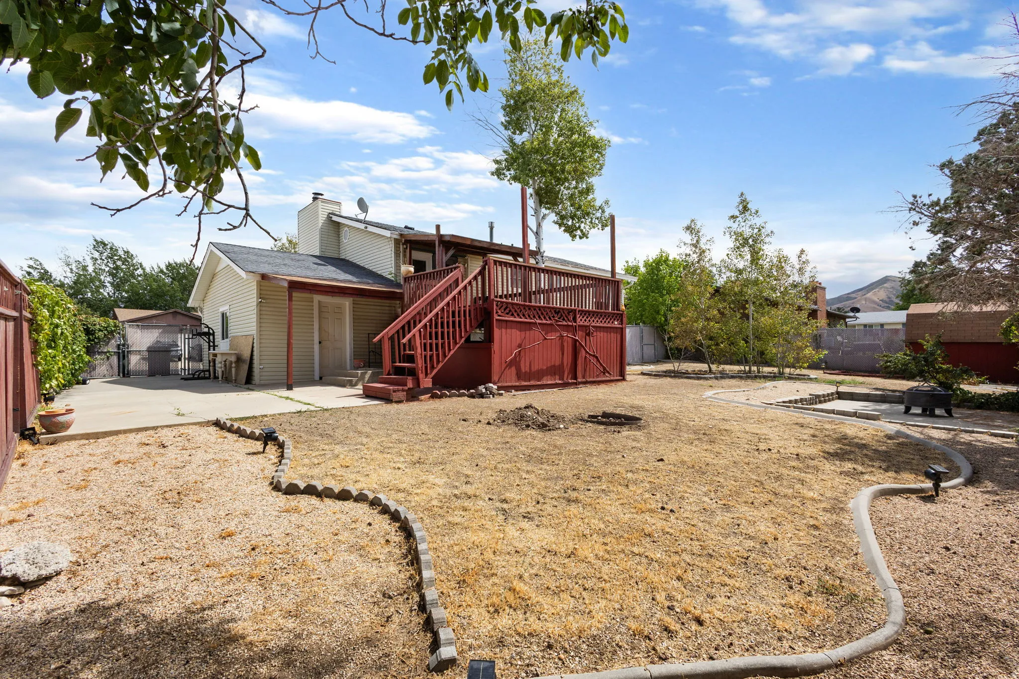 Multi-level wood deck with stairs, concrete patio, and a spacious yard with defined landscaping borders