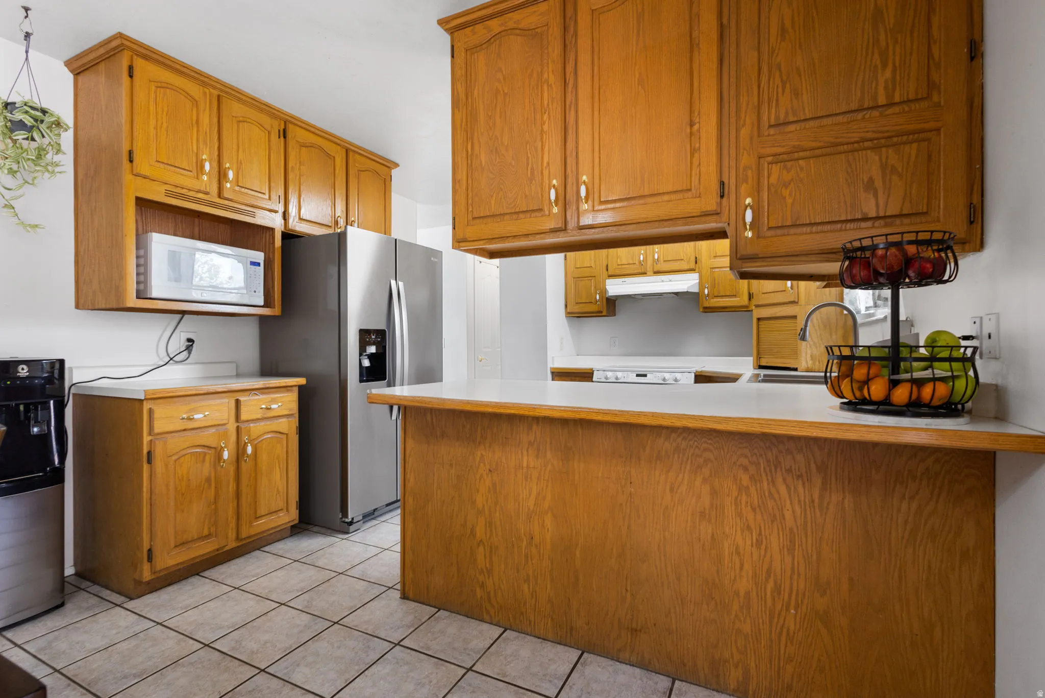 Wood-finish cabinetry paired with white countertops and white tiled flooring