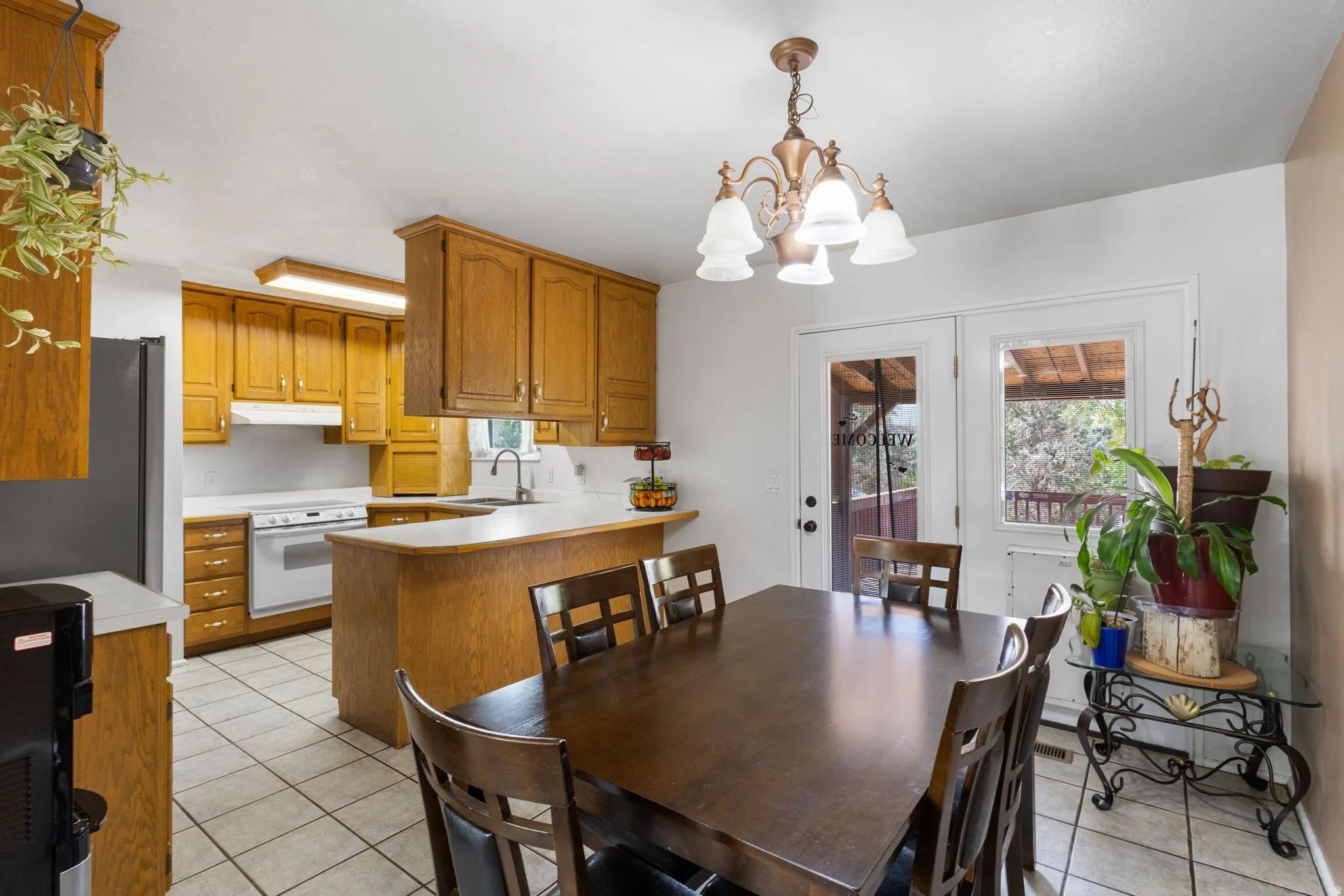 Kitchen and dining area featuring wood cabinetry, white countertops, tile flooring, and a glass-paneled exterior door