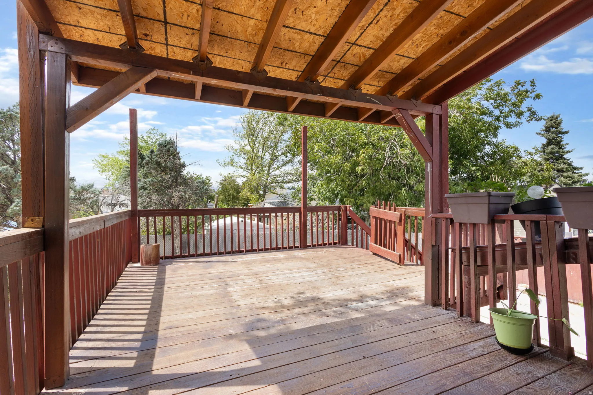 Expansive wood deck with a built-in pergola, wood railing, and a gate