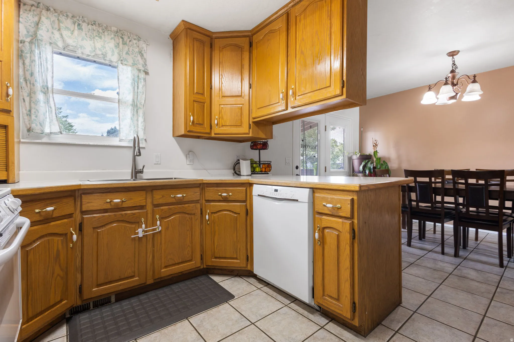 Kitchen featuring wood cabinetry, white countertops, a stainless steel faucet, and tile flooring