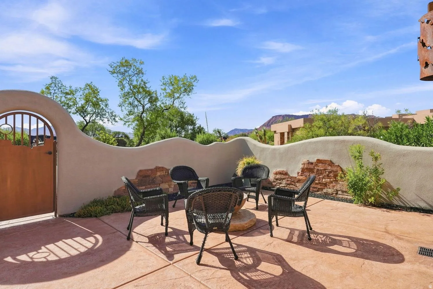 Stenciled concrete patio with a decorative privacy wall featuring exposed brick accents and an arched metal gate