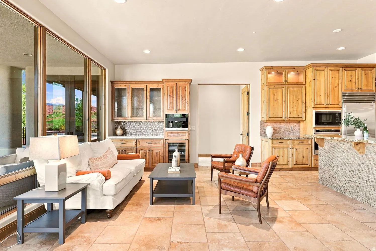 Expansive tile flooring throughout, full-height glass doors, custom wood cabinetry, built-in beverage refrigerator, and recessed lighting
