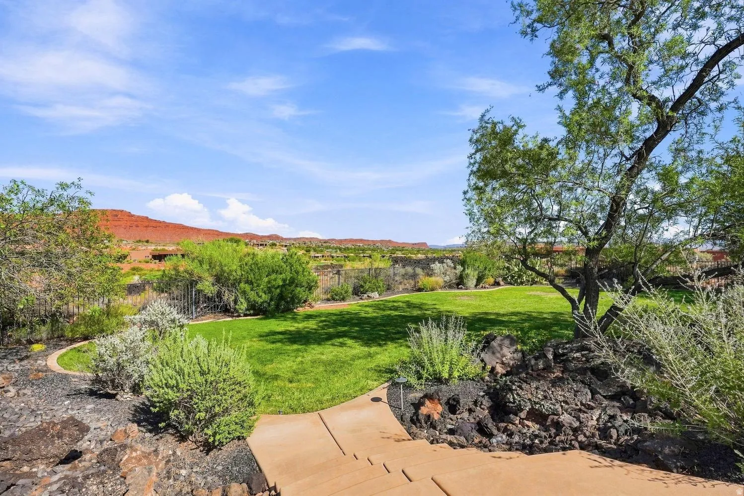 Expansive lawn bordered by mature trees and native landscaping