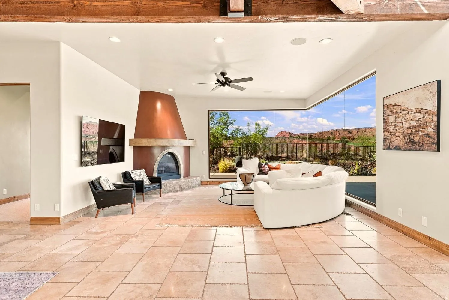 Exposed wood beams, tiled flooring, built-in fireplace with a copper hood, modern ceiling fan, and expansive floor-to-ceiling windows