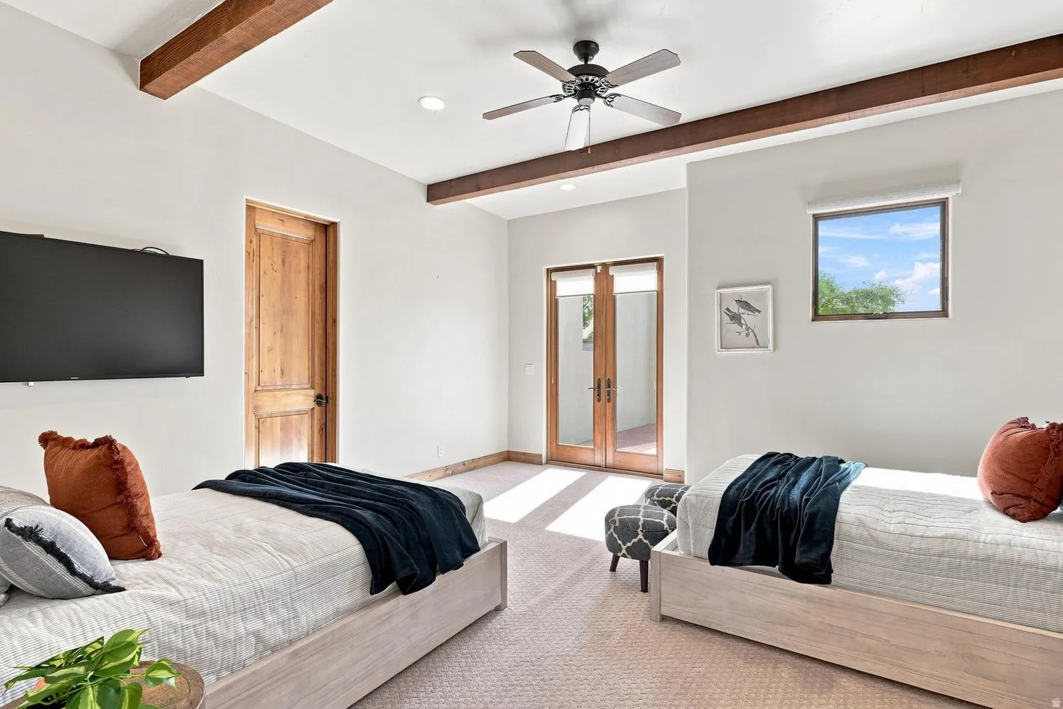 Vaulted ceiling with wood beams, light-toned carpeting, wood-paneled door, ceiling fan, and French doors