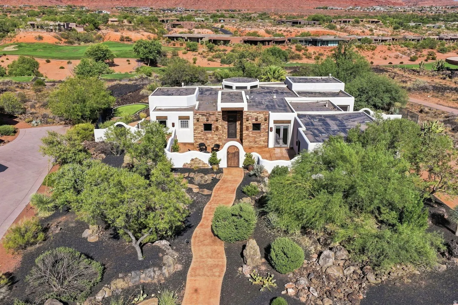 Southwestern-style architecture featuring a stone and stucco exterior, a flat roof, and an arched entry