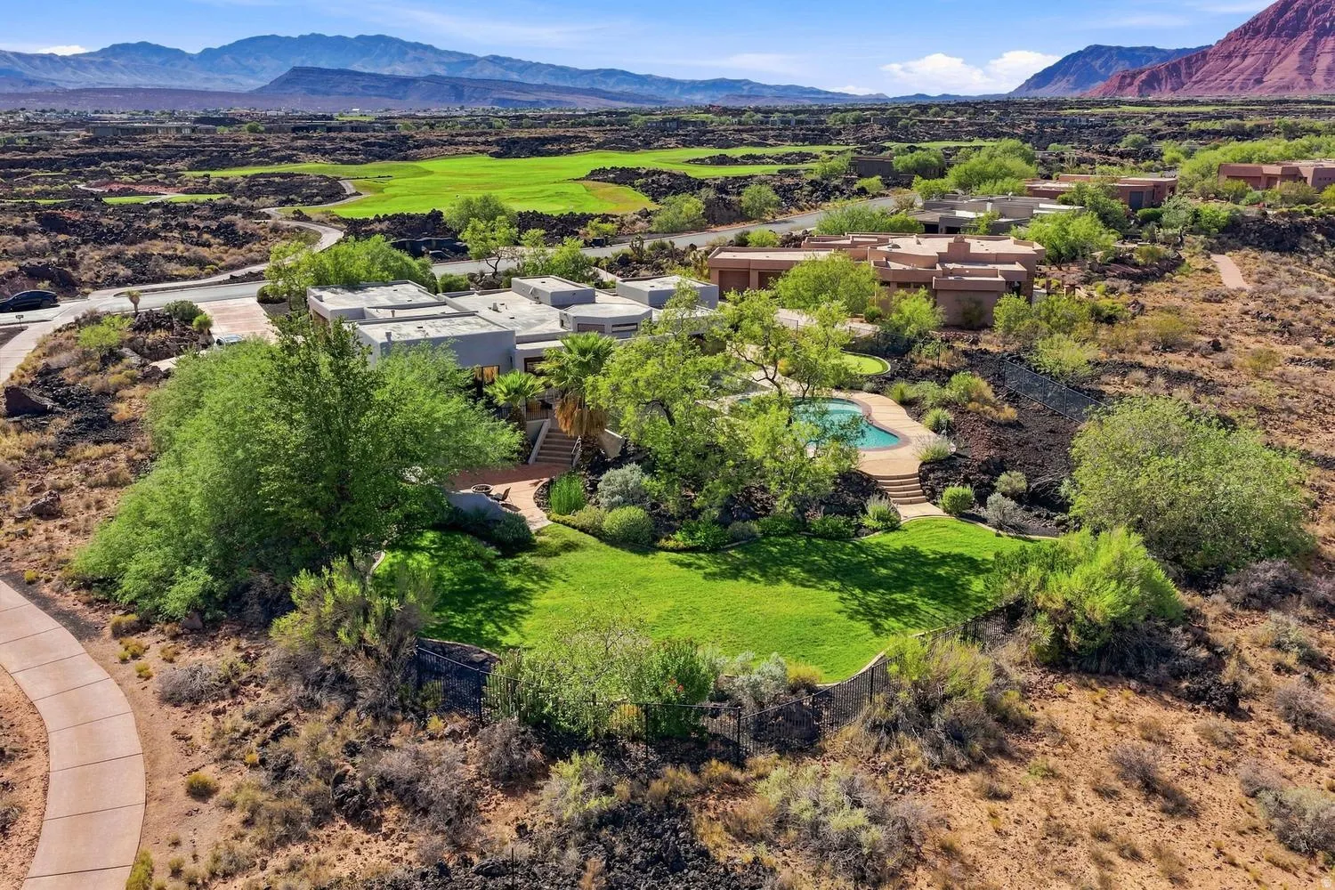 Outdoor swimming pool, manicured lawn, surrounding desert landscaping, paved walking path, and distant mountains