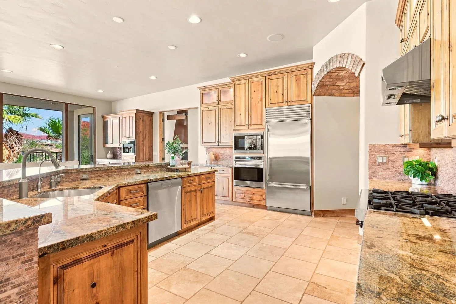 Spacious kitchen featuring natural wood cabinetry, stainless steel appliances, granite countertops, and tile flooring