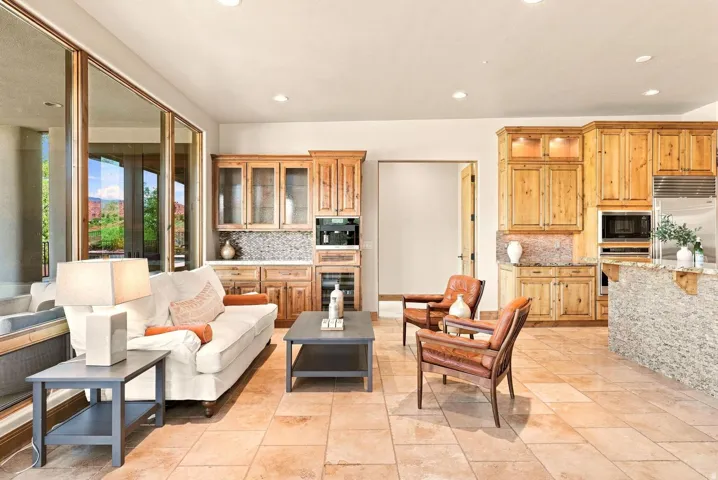 Expansive tile flooring throughout, full-height glass doors, custom wood cabinetry, built-in beverage refrigerator, and recessed lighting