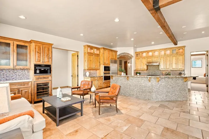 Expansive great room featuring a chef's kitchen with wood cabinetry, integrated appliances, and a mosaic tile backsplash