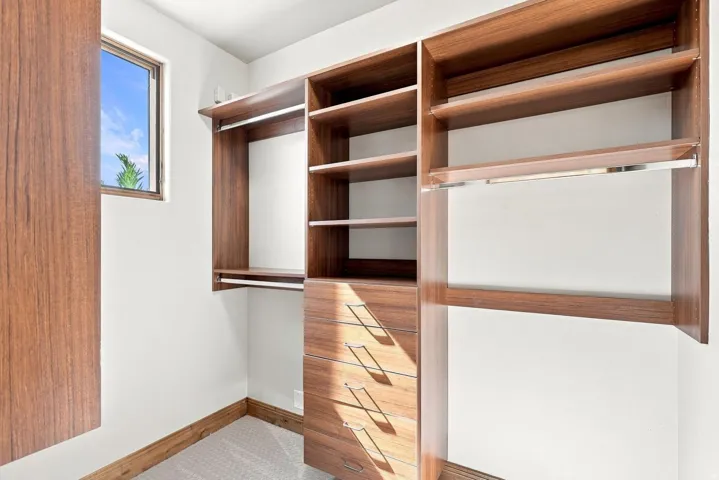 Custom wood-finish closet system featuring integrated shelving, multiple hanging rods, and built-in drawer storage