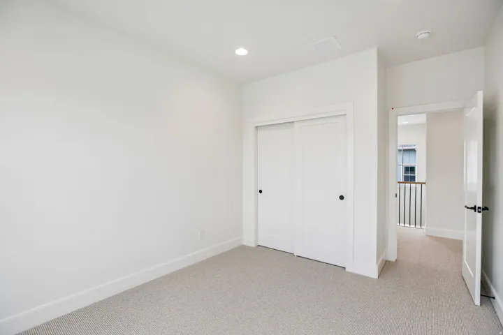 Light-toned carpeting and white walls with recessed ceiling lighting