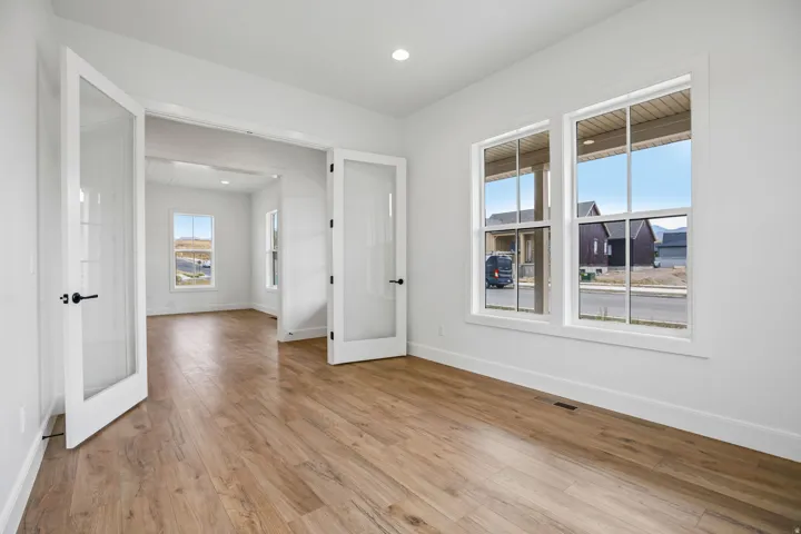 Wood-finish flooring throughout, bright white walls, and double French doors with frosted panels