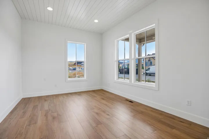 Wood-finish flooring, white walls, and a shiplap-style ceiling with recessed lighting