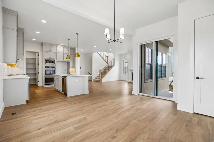 Kitchen island with seating, stainless steel appliances, wood-finish flooring, sliding glass doors, and a staircase with wood railings