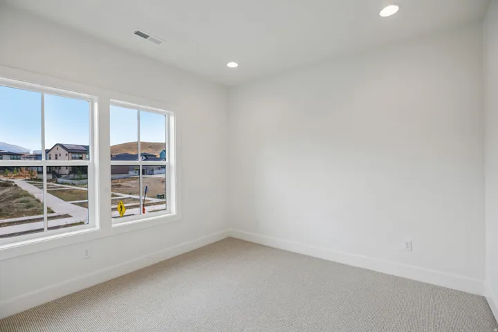 Dual windows providing natural illumination, recessed lighting, white wall finishes, and textured carpeting