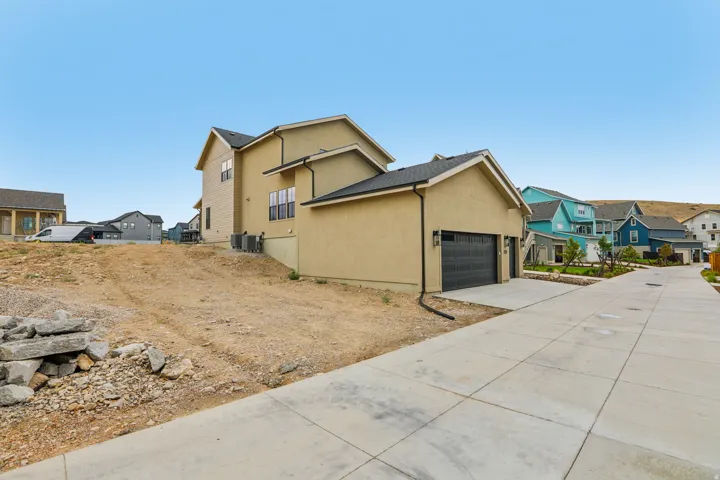 Stucco exterior with a two-car garage, concrete driveway, and black roof